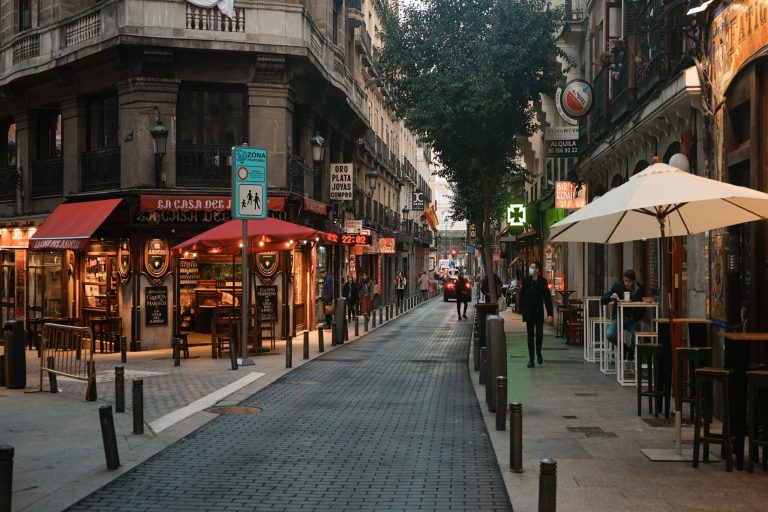 People walking on sidewalk near red and brown building during daytime, Madrid, Spain